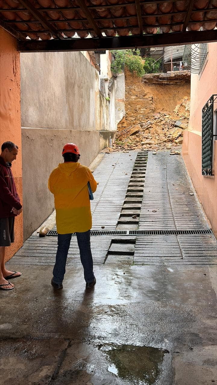 The access to the Ashrama's parking area, covered at the far end by earth and stones from the collapsed wall; a technician in a helmet looks on.