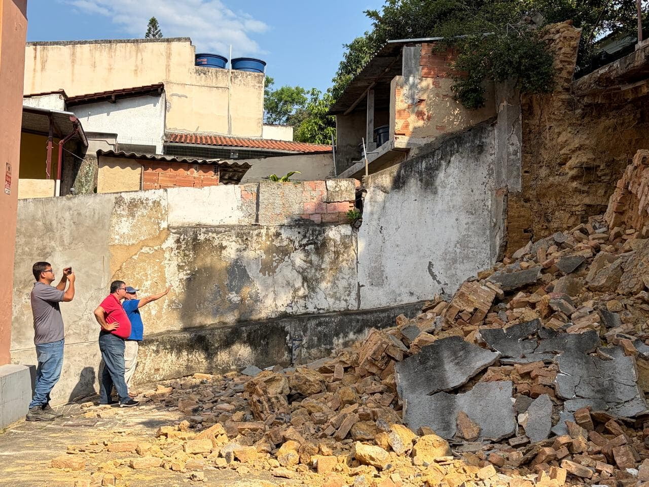 Engineers assess the collapsed retaining wall at the back of the Ashrama; bricks and rubble cover the parking area.